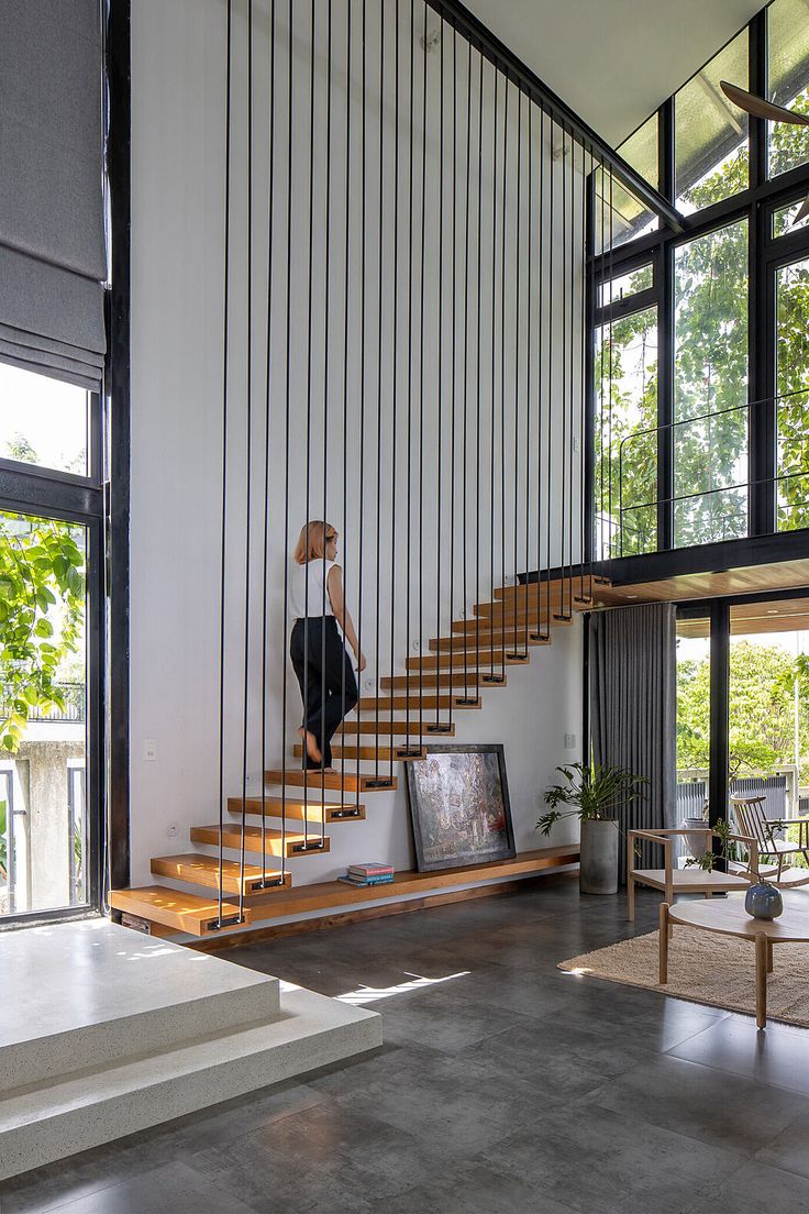 a woman is walking up the stairs in a modern house