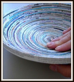 a person is holding a plate made out of newspaper strips with their hands on it