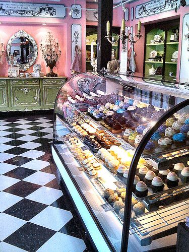 a bakery filled with lots of cupcakes on display in front of a checkered floor