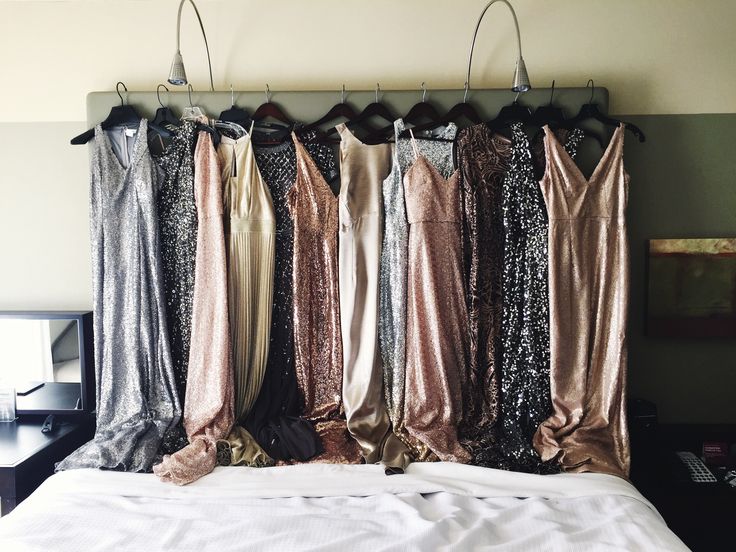 there are many dresses hanging up on the clothes rack above the bed in this room