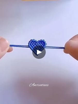 two hands holding a blue string with a heart on it and another hand holding the string