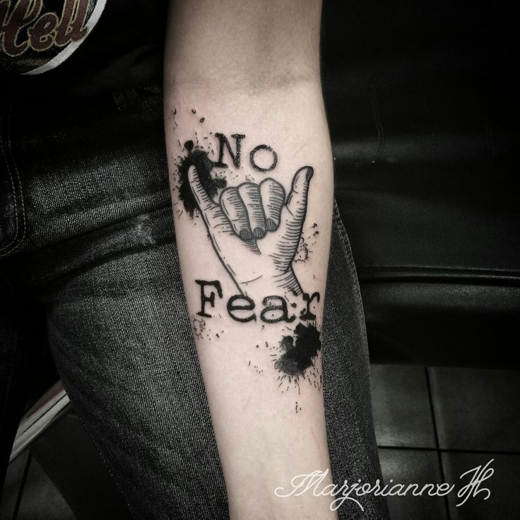 a person with a tattoo on their arm that reads no fear and has ink splatters all over it