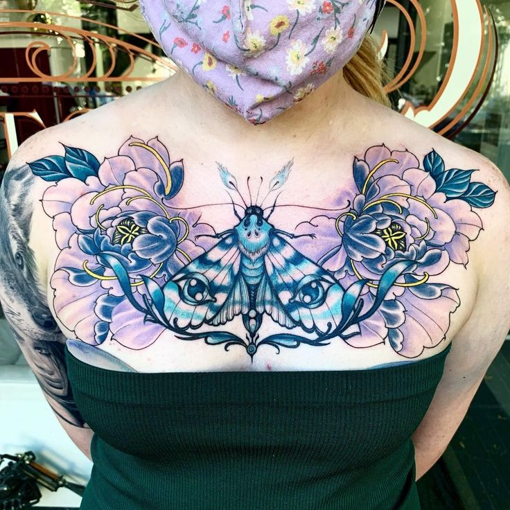 a woman with a butterfly tattoo on her chest, wearing a purple scarf over her head