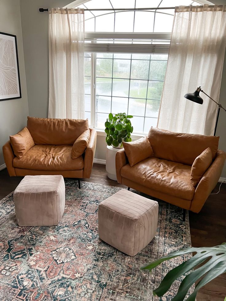 a living room with two couches and a rug in front of a large window