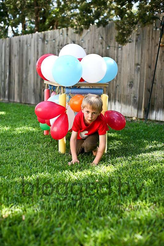 a little boy playing in the grass with balloons