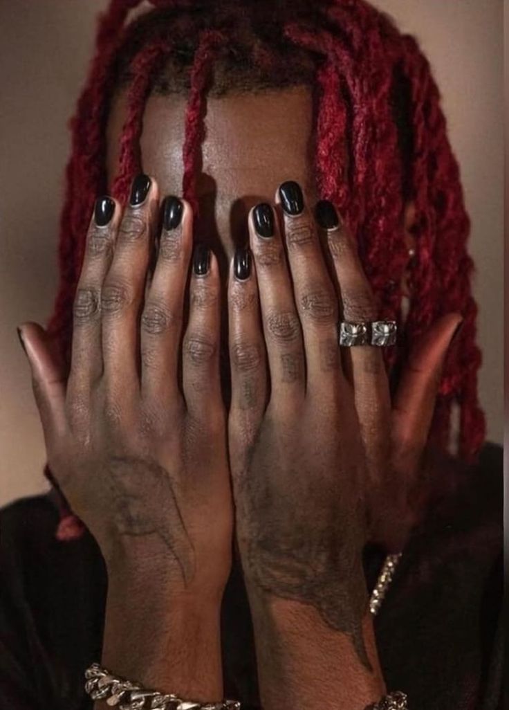 a woman with red dreadlocks covering her face and hands in front of her face