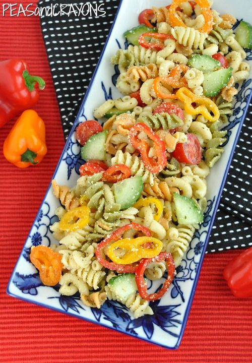 pasta salad with peppers and cucumbers in a blue and white plate on a red tablecloth