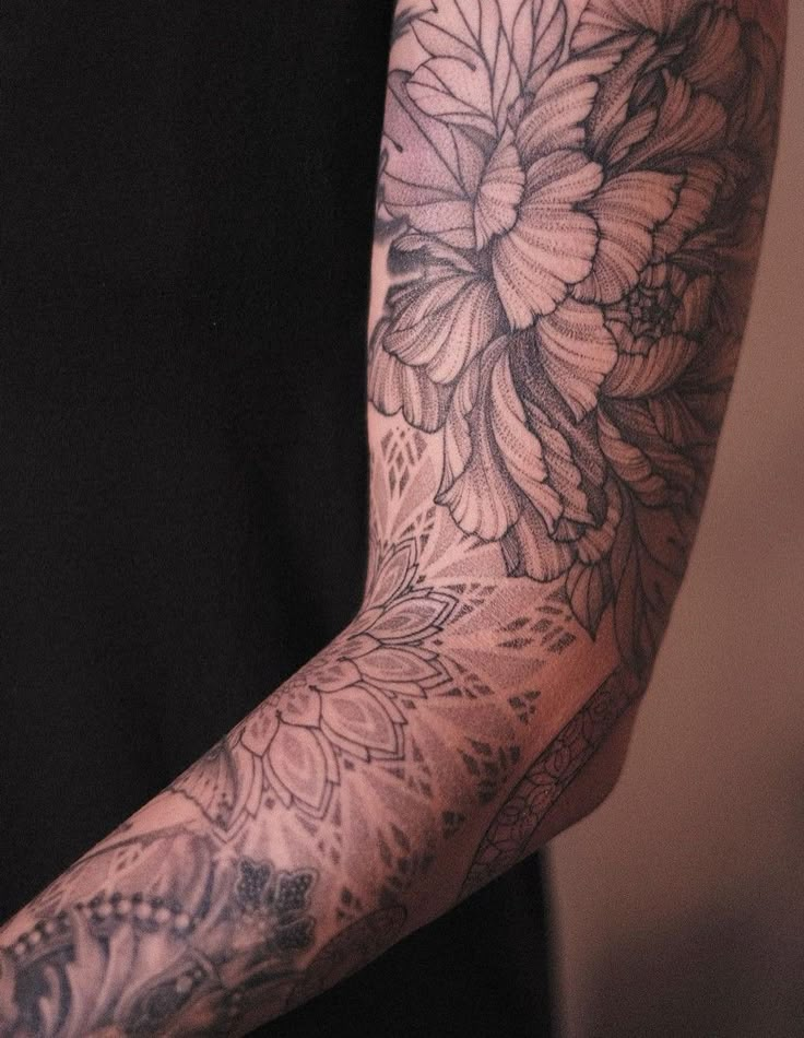 a man's arm with flowers on it is shown in black and grey colors