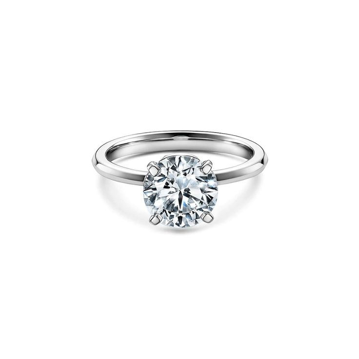 a white gold engagement ring with a round brilliant diamond in the center, on a plain surface