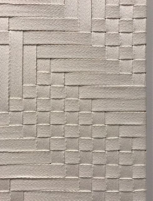 an abstract painting with white squares and lines on the wall, as if it were woven into fabric