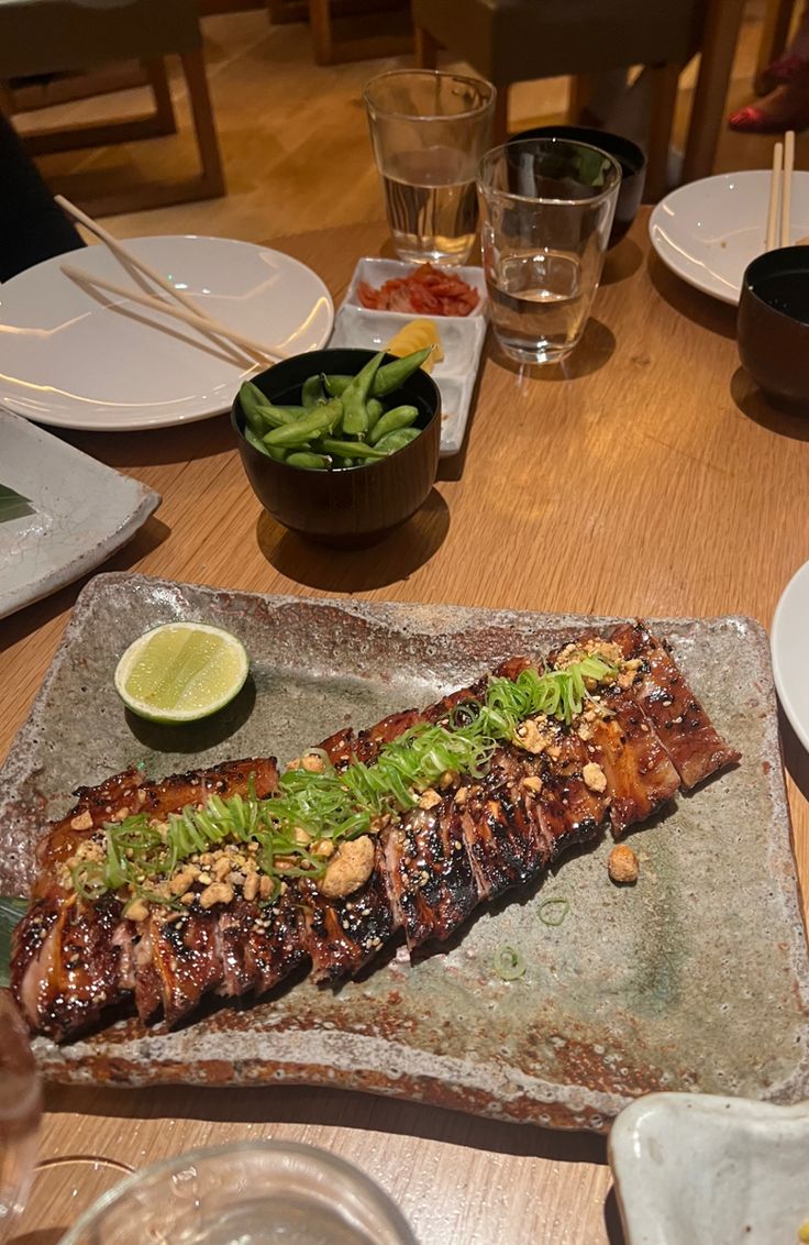 a piece of meat sitting on top of a wooden table next to plates and glasses