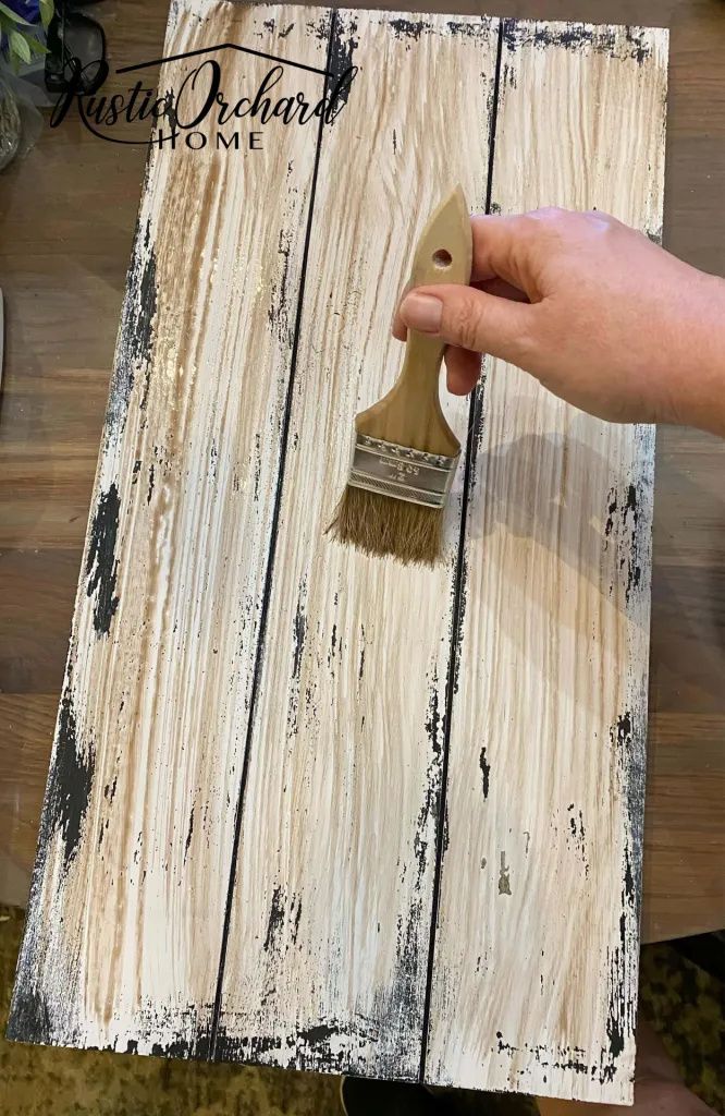 someone using a brush to paint wood planks