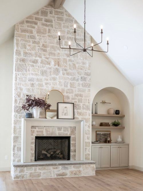 a living room filled with furniture and a fire place in front of a stone wall