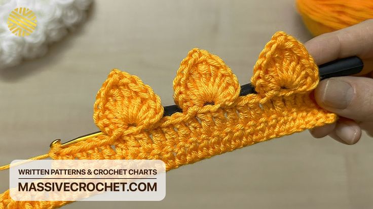 someone is crocheting an orange piece of yarn with two small bows on it