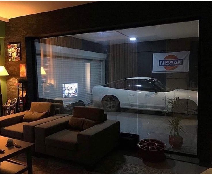 a living room filled with furniture and a white car in the reflection on the wall