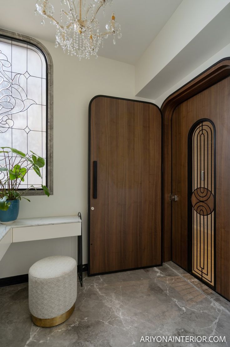 a room with two wooden doors and a white stool in front of the door that has a glass window