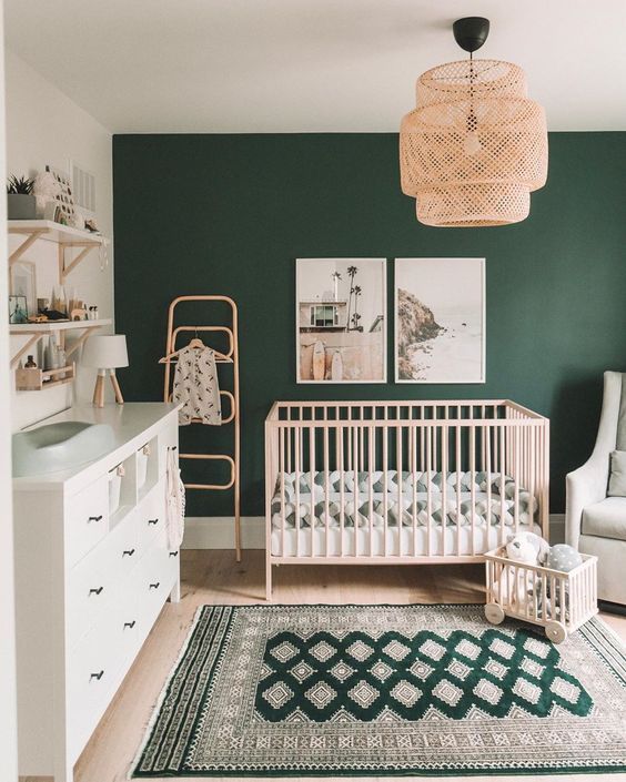 a baby's room with green walls and white furniture