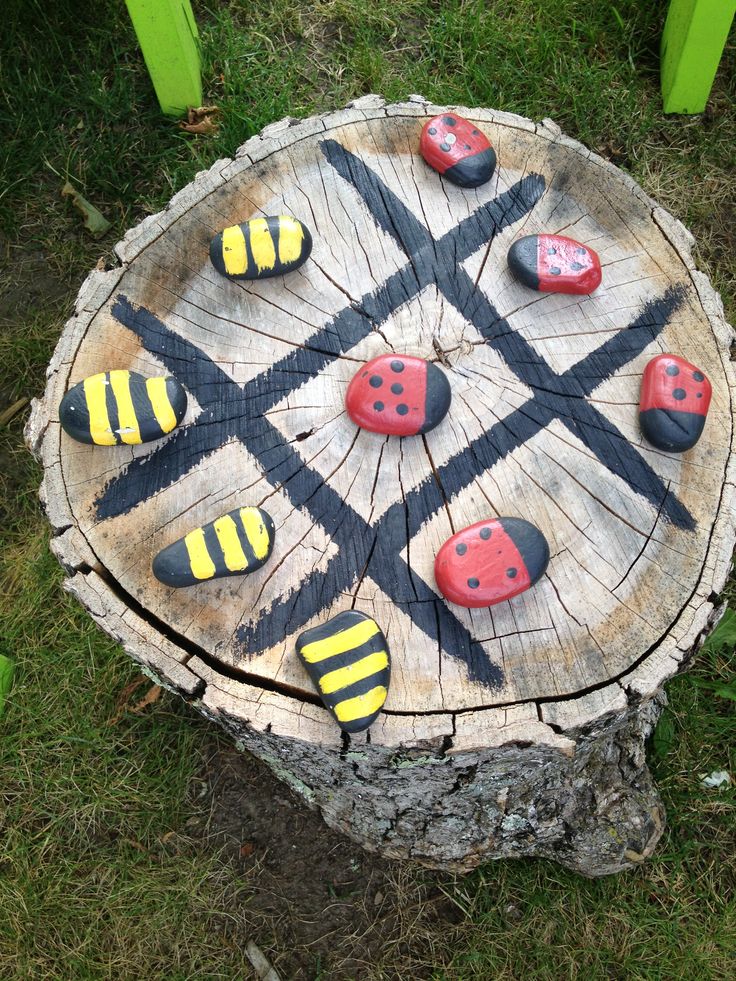 painted rocks are arranged on top of a tree stump in the shape of ladybugs