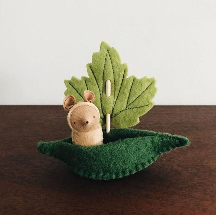 a small stuffed animal sitting on top of a green leaf