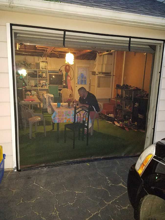 a man sitting at a table in front of a garage door with the glass open