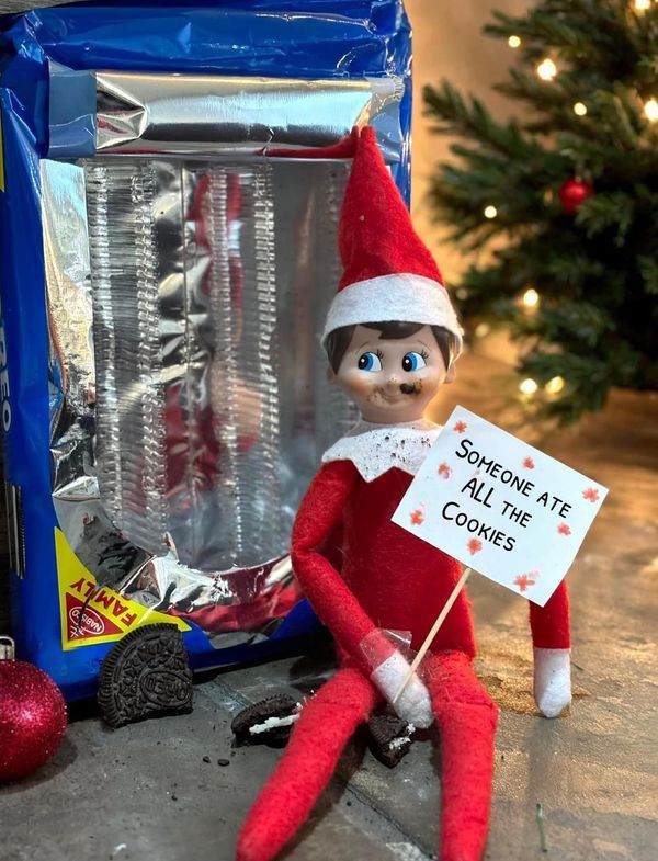 an elf holding a sign next to some candy