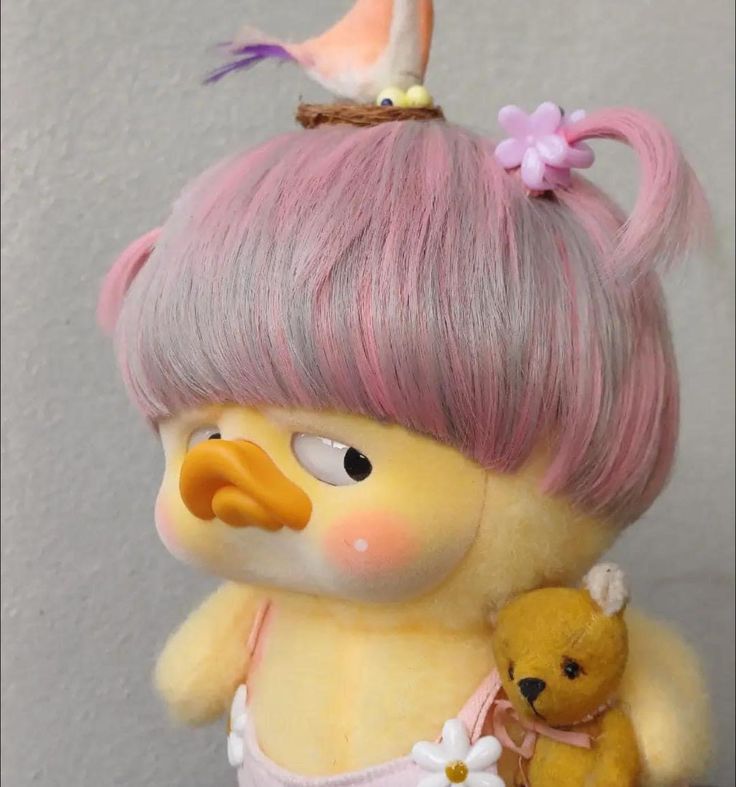 a doll with pink hair holding a teddy bear and wearing a flower in her hair