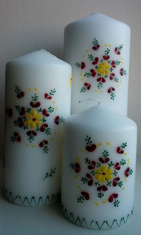 three white candles with red and yellow flowers on them