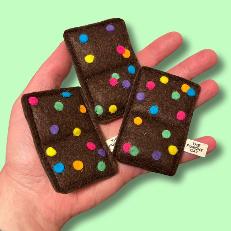 hand holding three brown felt squares with multicolored polka dots