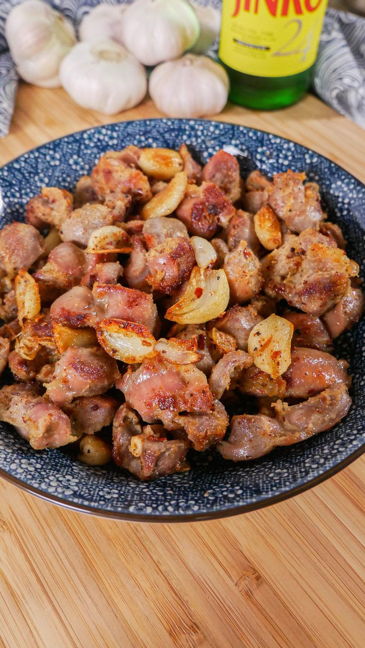 a blue plate topped with meat and onions next to garlic on a wooden counter top