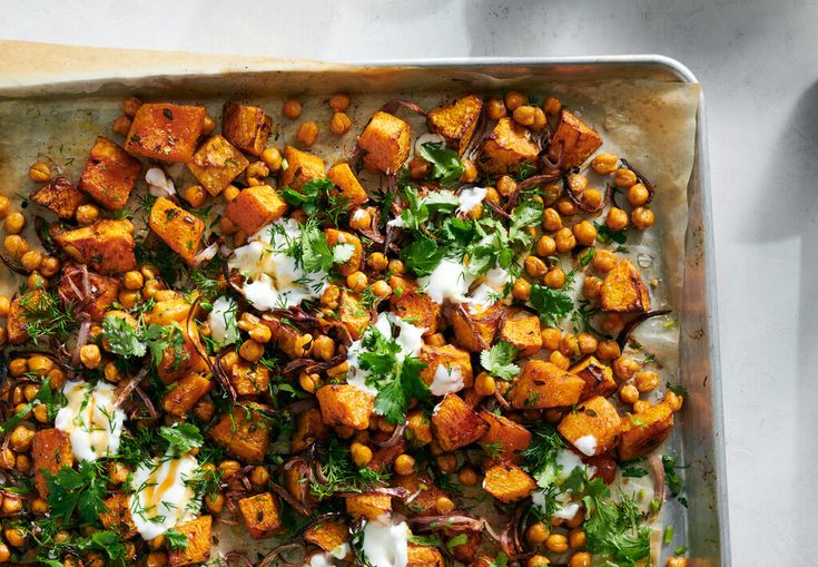 a pan filled with chickpeas and other vegetables on top of a sheet of parchment paper