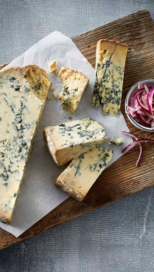 cheese and onion on a cutting board with a bowl of pickled up radishes