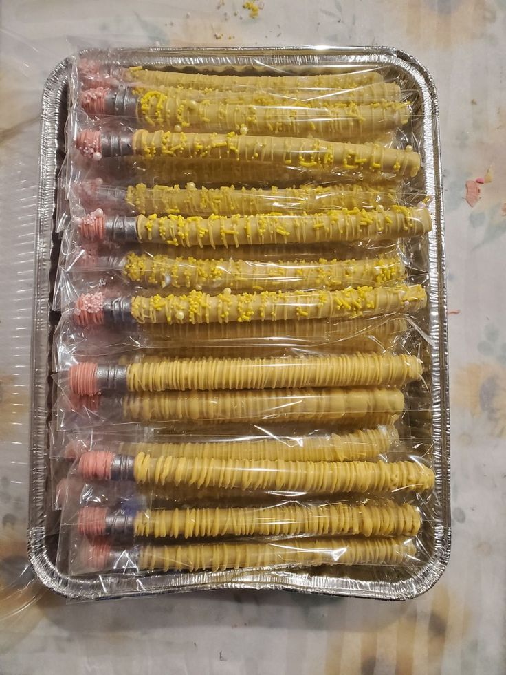 a tray filled with lots of yellow and red pasta noodles on top of plastic wrap