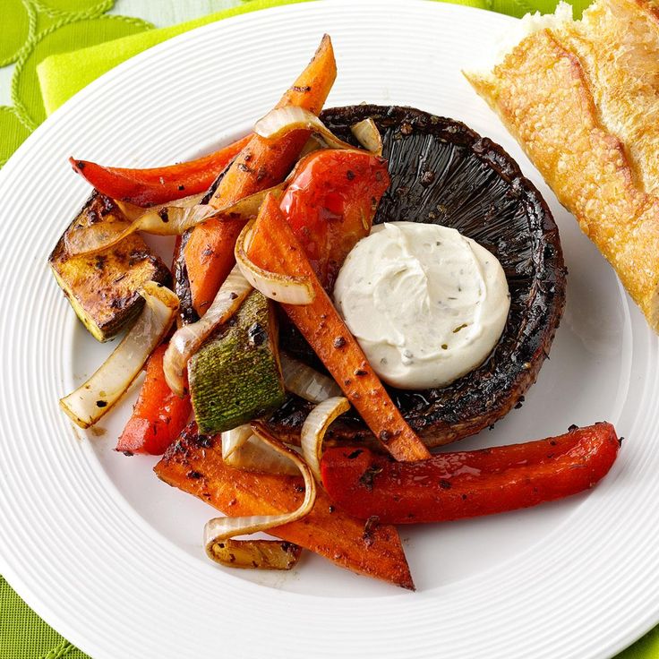 a white plate topped with meat and veggies next to a flat bread roll