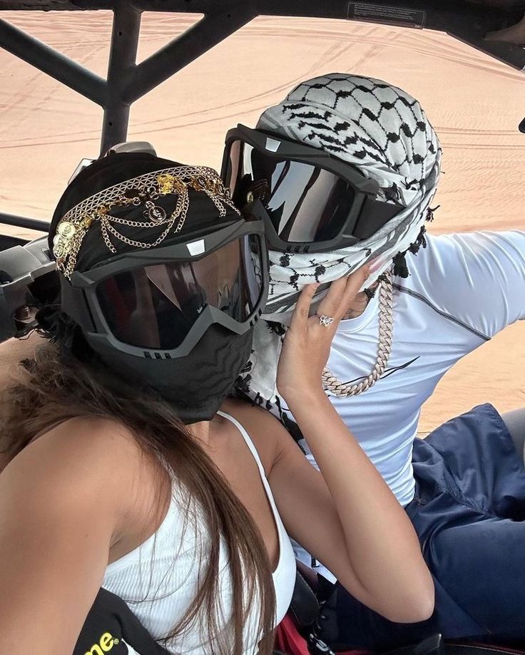 two people sitting in a vehicle with helmets on