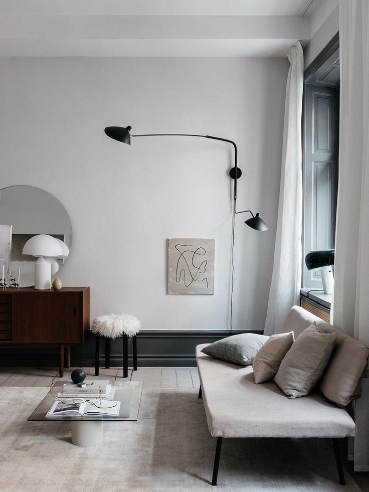 a living room filled with furniture and a large mirror on the wall next to a window