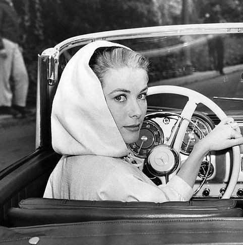 a man and woman sitting in the driver's seat of a car, both wearing head coverings