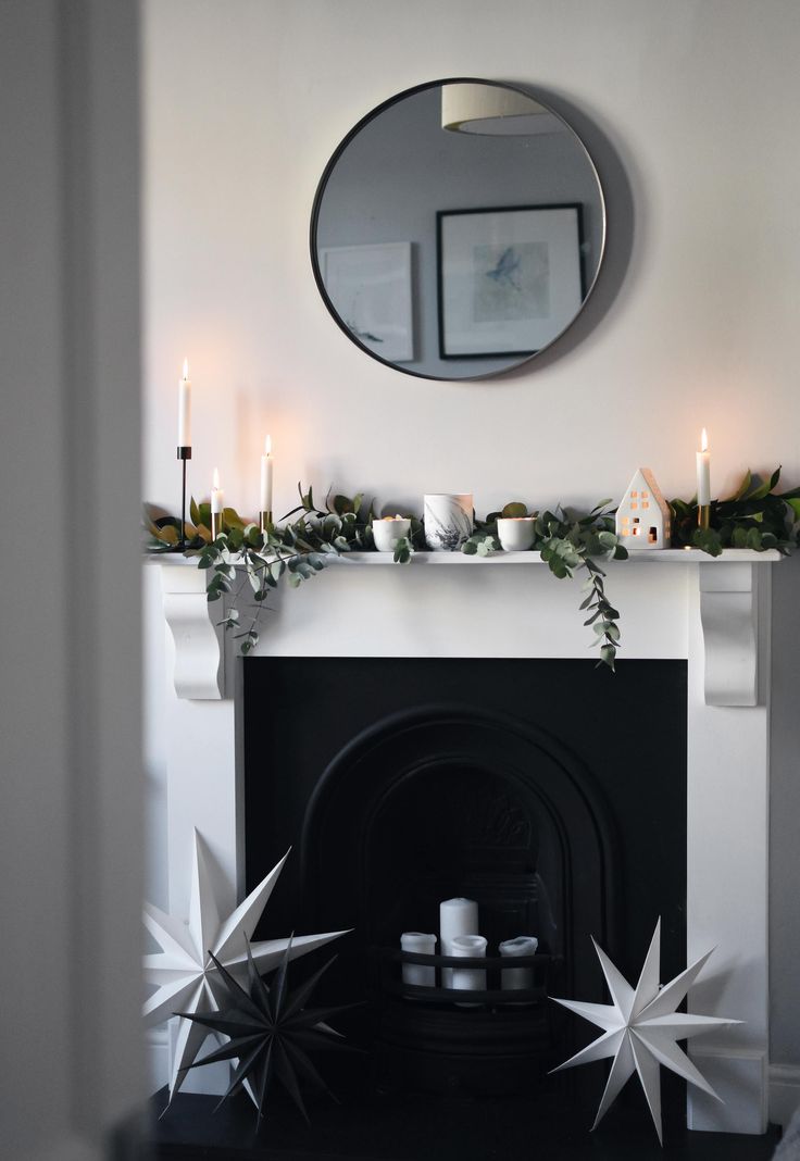 a living room with a fire place and mirror on the fireplace mantel, decorated for christmas