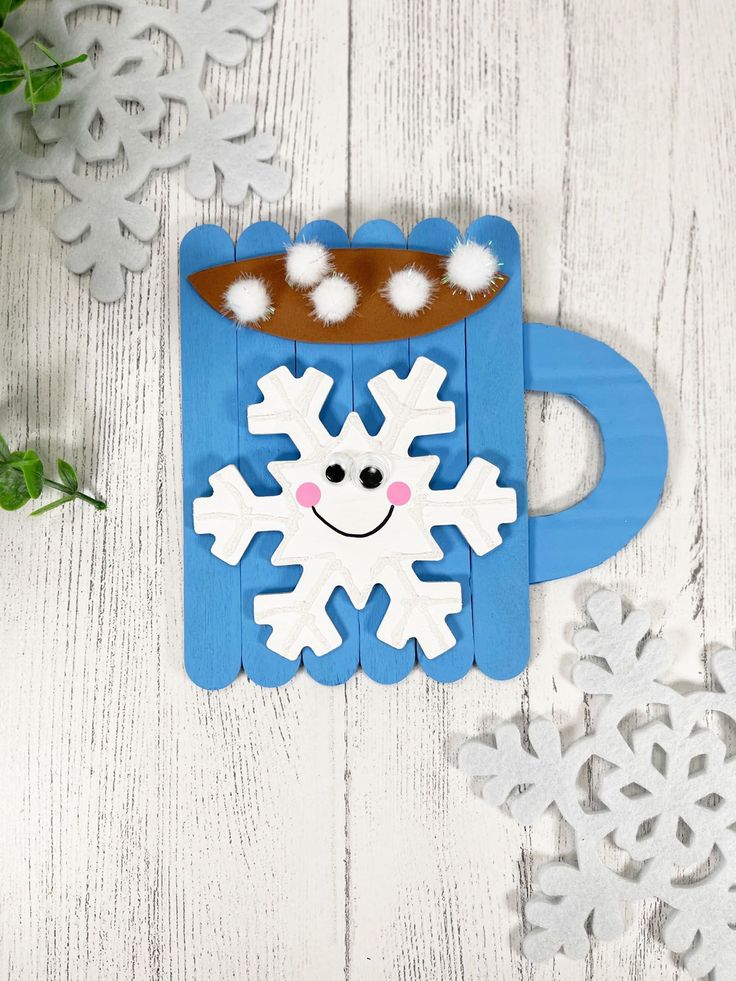 a paper cup with snowflakes on it sitting next to some cut out snowflakes