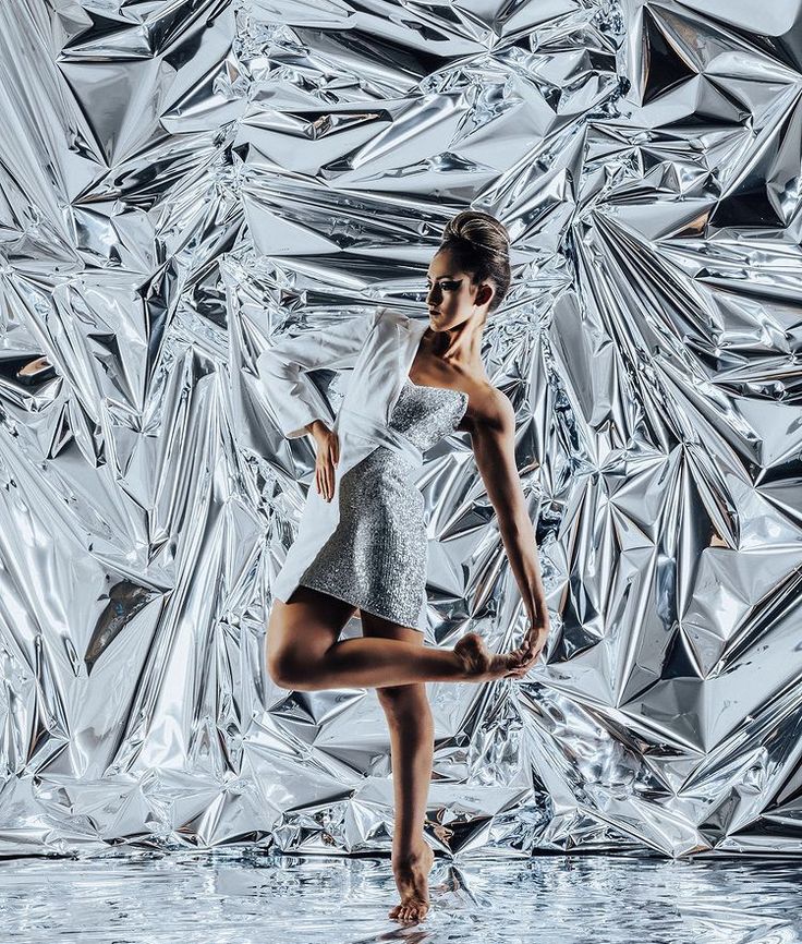 a woman is dancing in front of an artistic background that looks like tinfoils