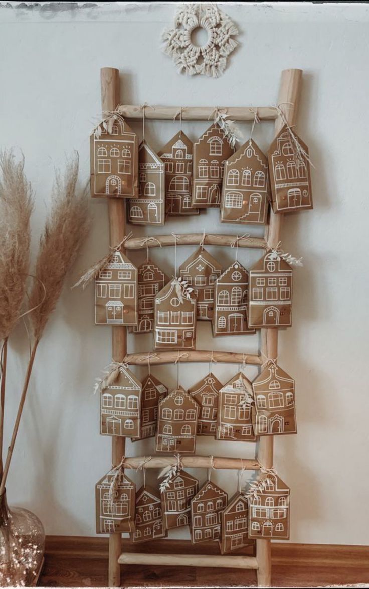 a group of gingerbread houses hanging on a wall next to a vase with dried grass