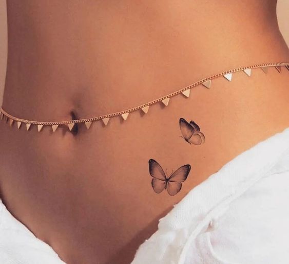 a woman's stomach with two butterflies on it and a chain attached to the side