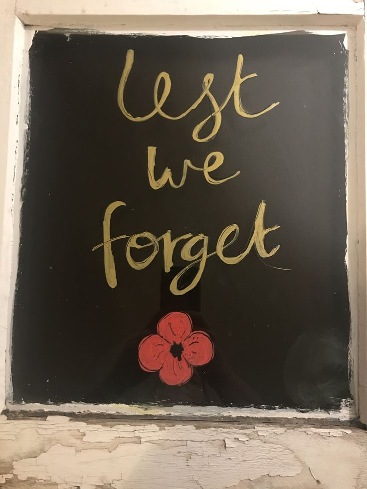 a sign that says, best we forget on the side of a building with a flower painted on it