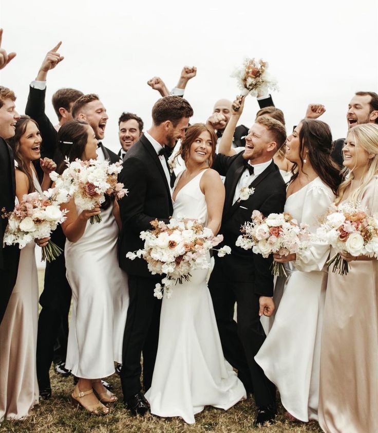 a group of people standing next to each other holding bouquets in their hands and posing for the camera