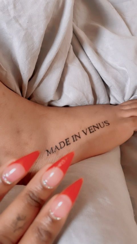 a woman's foot with the words made in venus tattooed on her left side