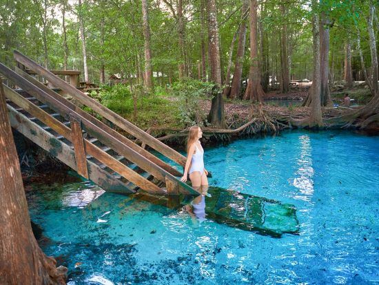 a woman standing in the middle of a blue pool with stairs leading up to it