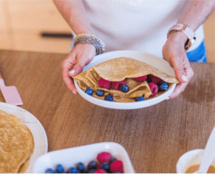 a person holding a plate with food on it and some fruit in the other hand