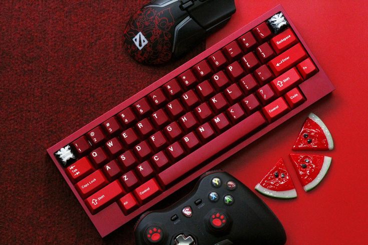 a red keyboard, mouse and some slices of watermelon on a red surface