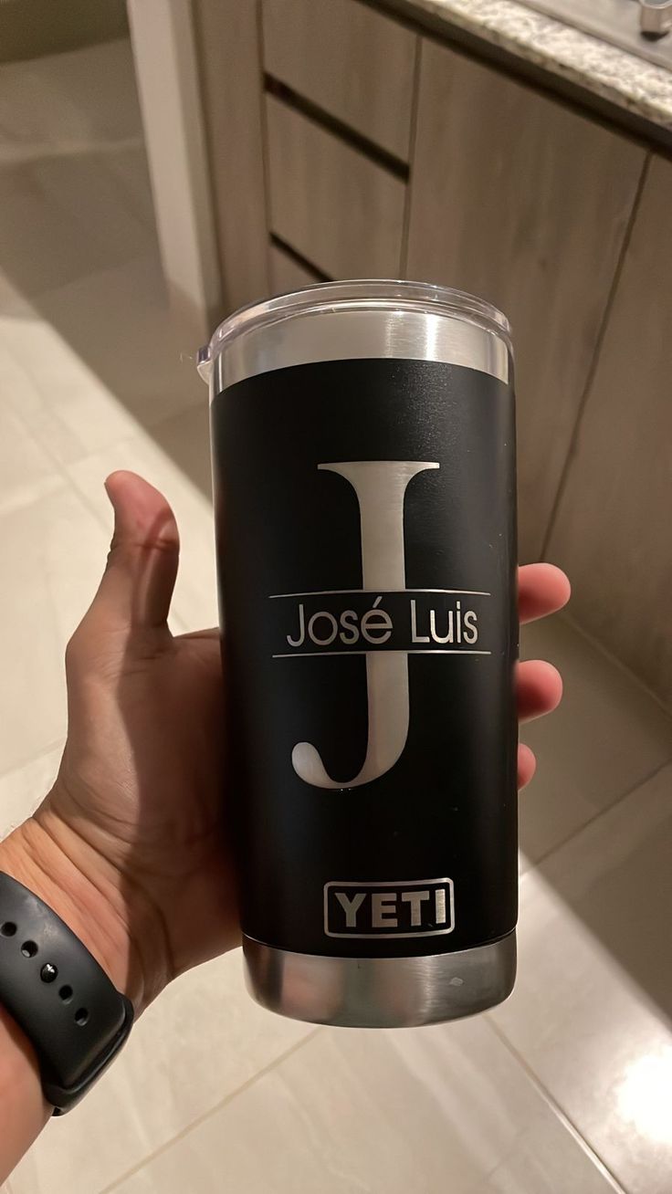 a person holding up a tumbler cup with the j on it's side