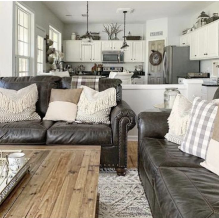 a living room with two couches and a coffee table in front of the kitchen