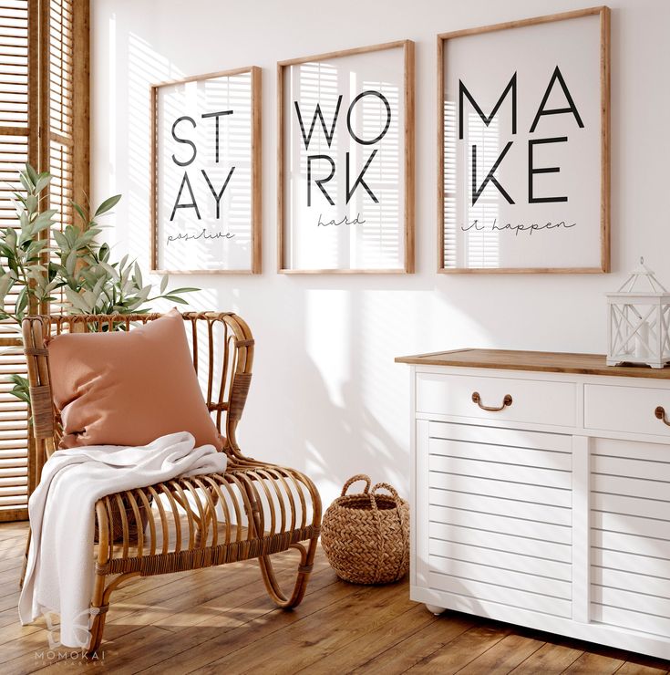 a white room with three framed posters on the wall and a wicker chair next to it